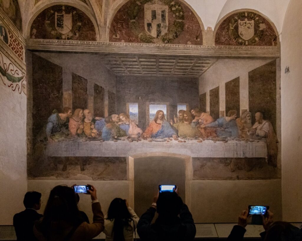 Visitors eagerly capture photos of Leonardo da Vinci's iconic "The Last Supper" mural in Milan, a highlight featured prominently in any Milan travel guide. This masterpiece, depicting Jesus and his disciples, draws crowds to the city's renowned museum.