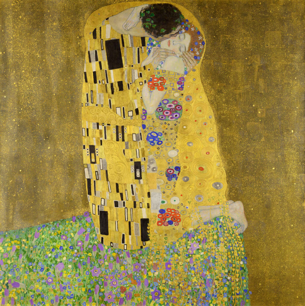 A man and woman embrace and kiss, wrapped in a gold-patterned robe, kneeling on a flower-covered ground against a gold background.