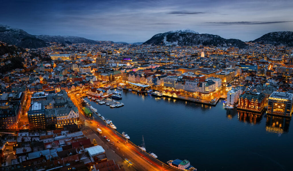 Aerial view of Bergen dusk with illuminated buildings surrounding a harbor