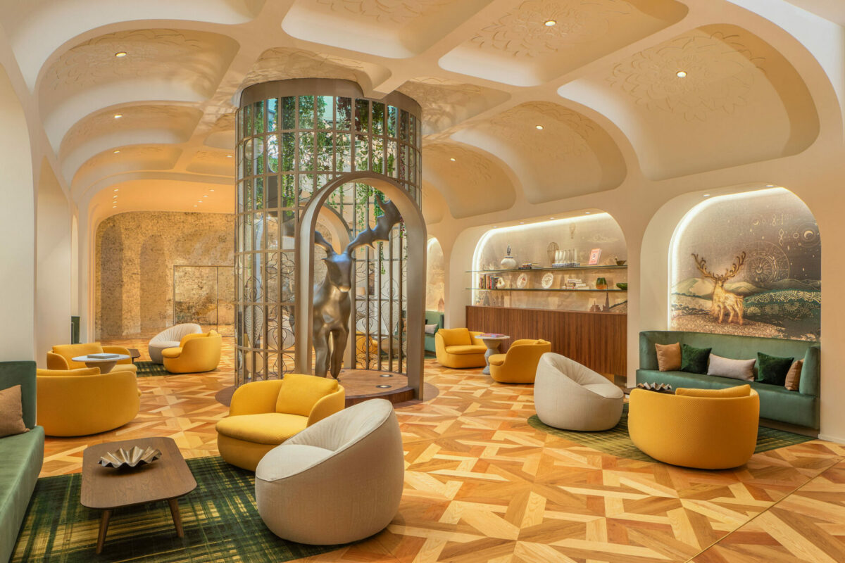 Hotel lobby with mustard and cream chairs, and golden stag scultpure in centre