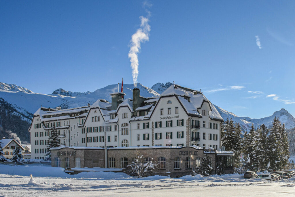 Cresta Palace Celerina, Four-star hotel in a snowy landscape with mountains in the background, in Engadin, Switzerland.