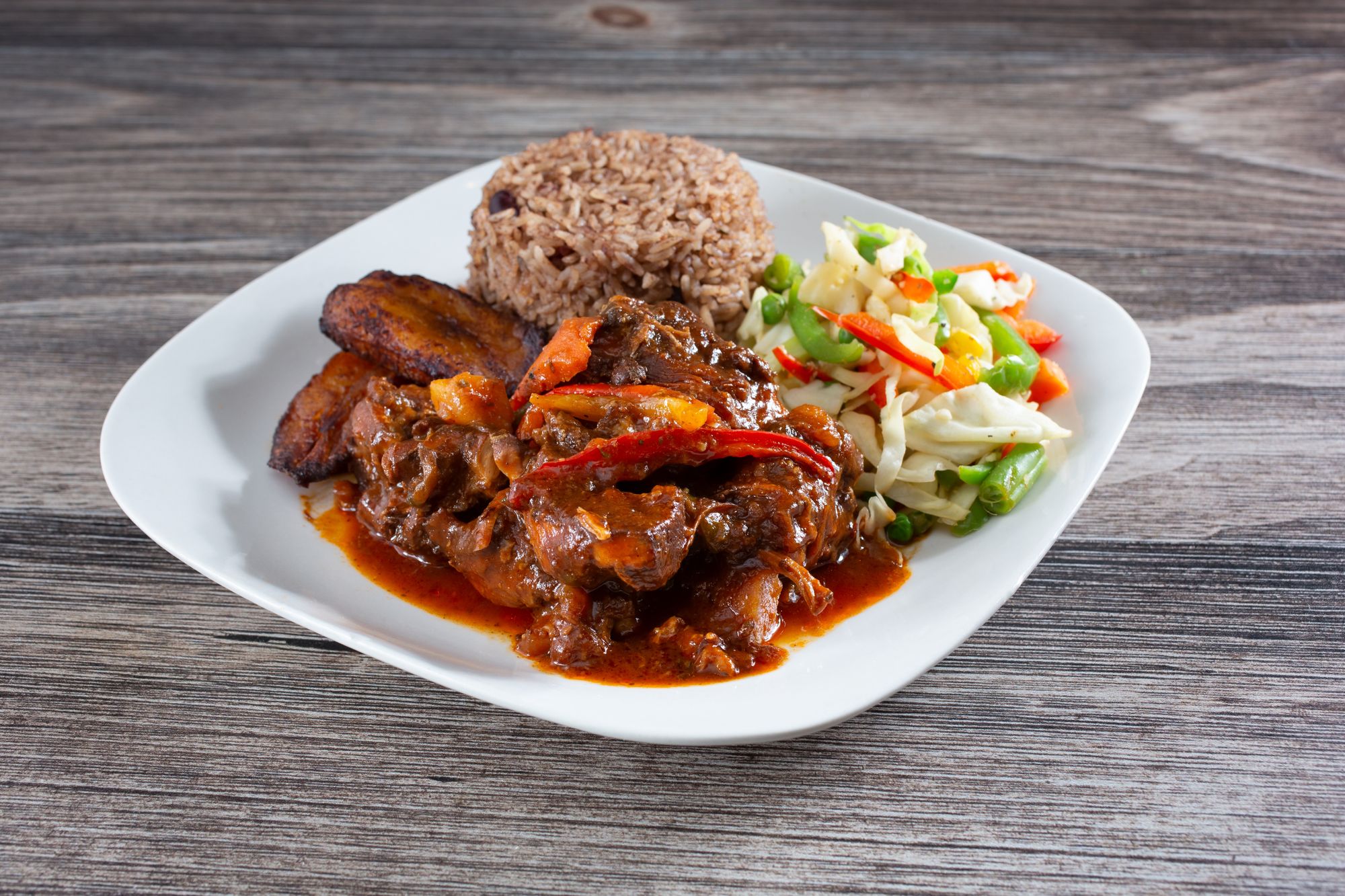 brown stew chicken served with fried plantain black bean rice and assorted veggies