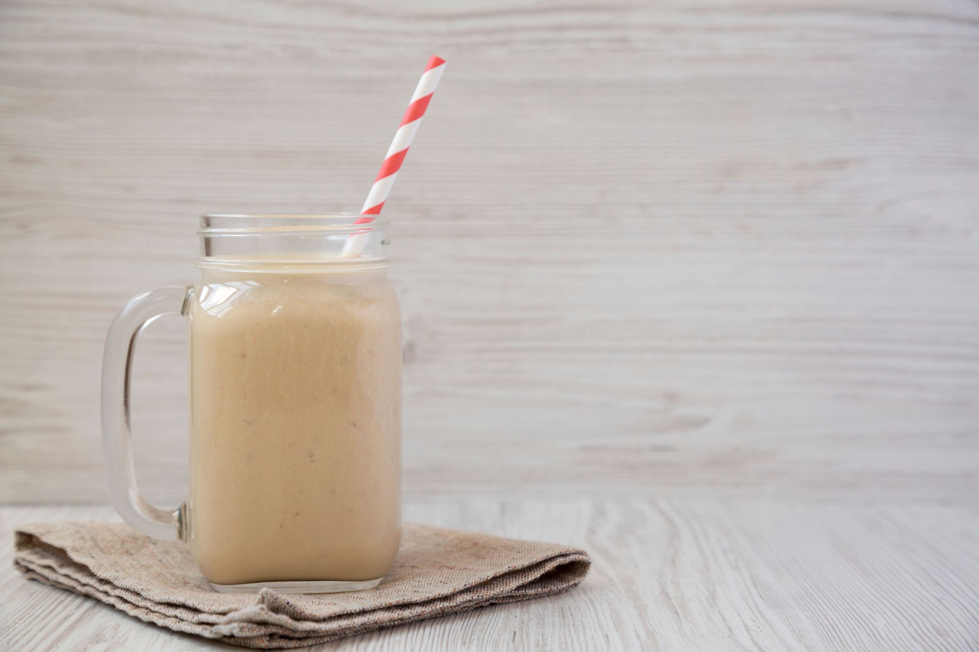 jamaican peanut punch in a mason jar on a cloth with a straw