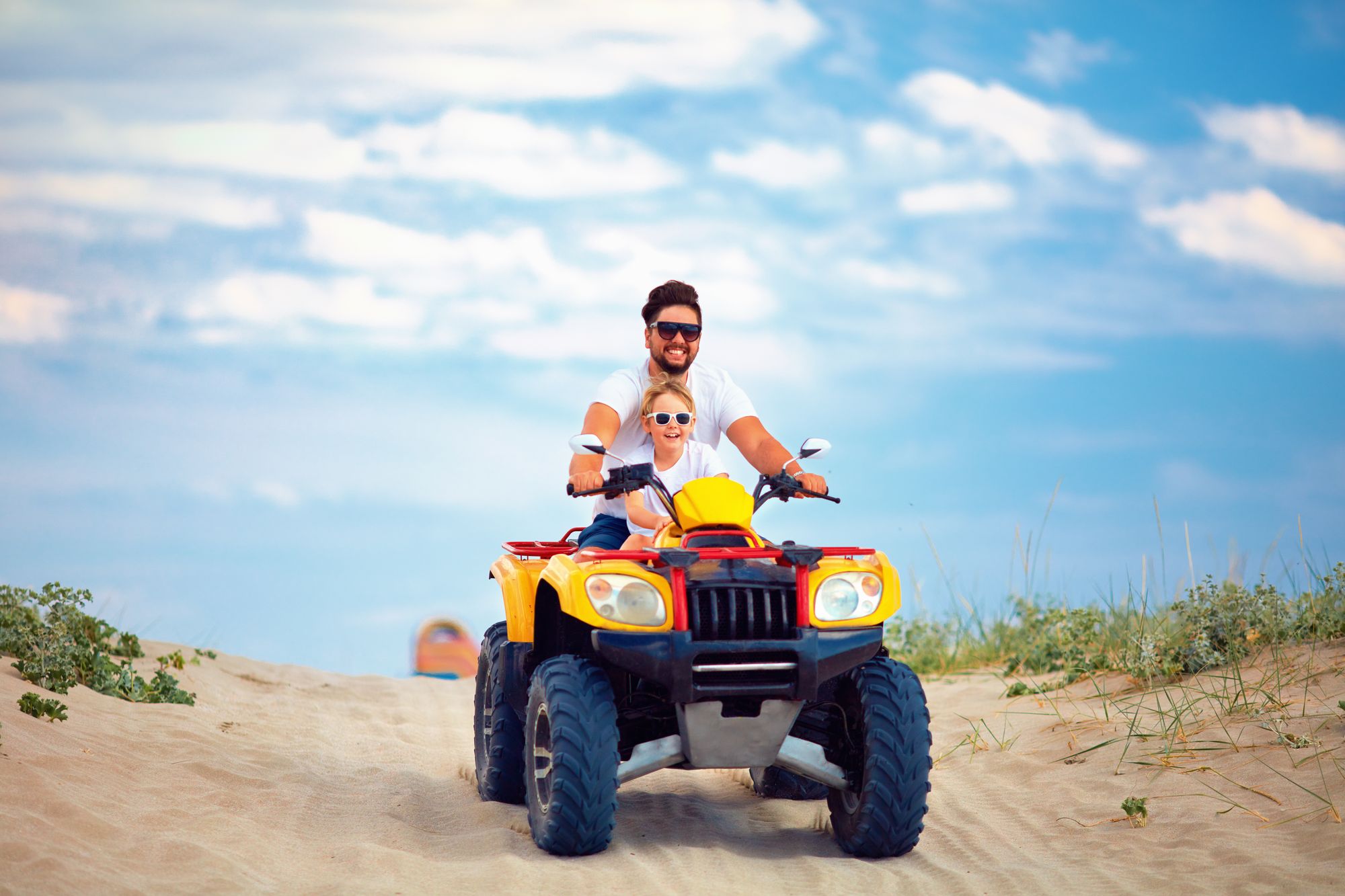 father and son riding atv on beach